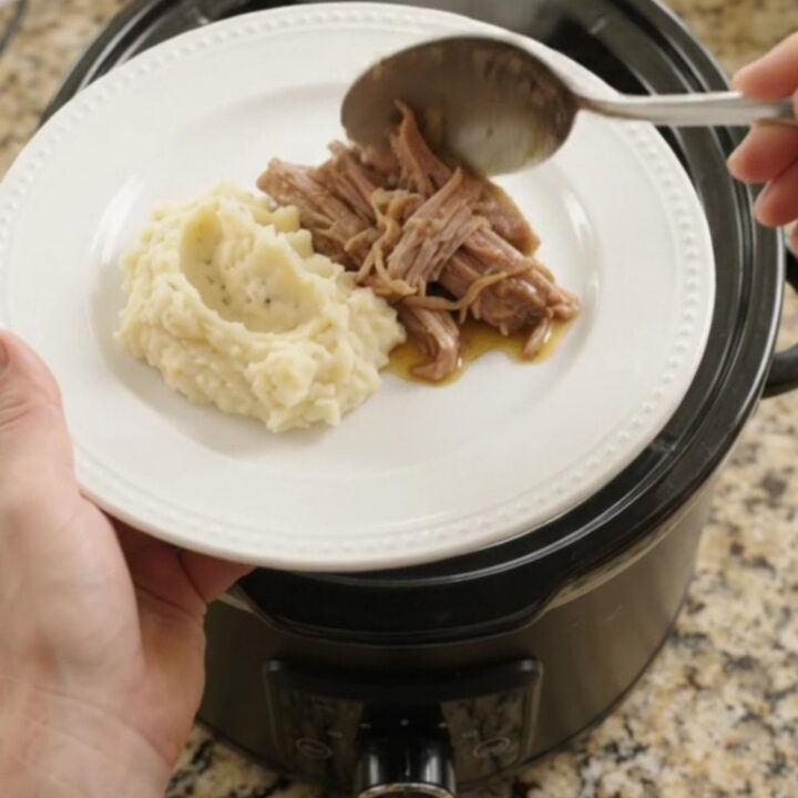 Pulled pork shoulder with portobello mushrooms in a slow cooker, topped with butter