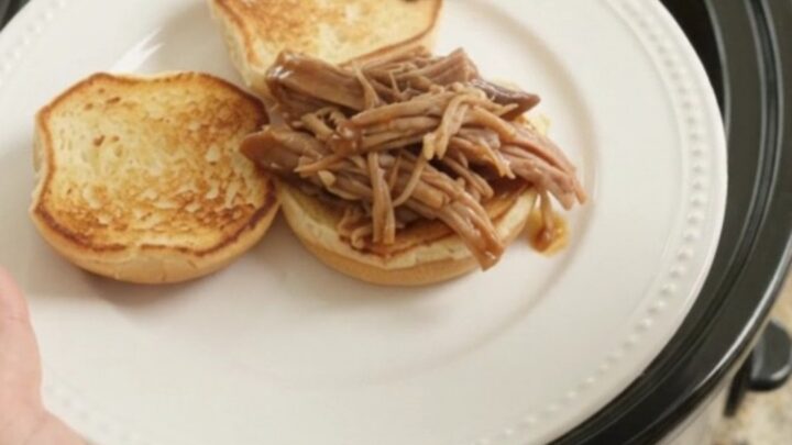 Slow-cooker portobello brown gravy pork shoulder shredding in a black crockpot