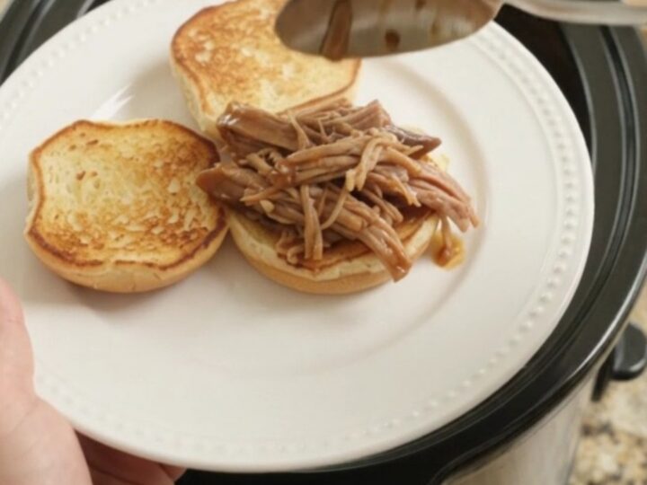 Slow-cooker portobello brown gravy pork shoulder shredding in a black crockpot