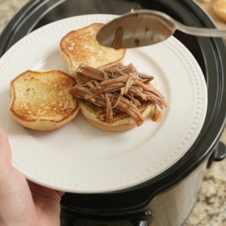 Slow-cooker portobello brown gravy pork shoulder shredding in a black crockpot