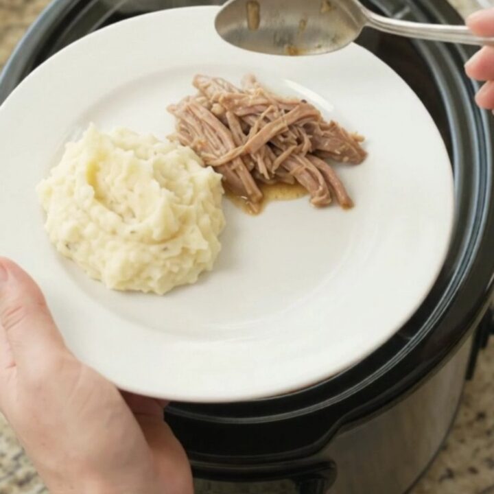 Slow cooker pork shoulder with peppers and onions in a glossy black crock