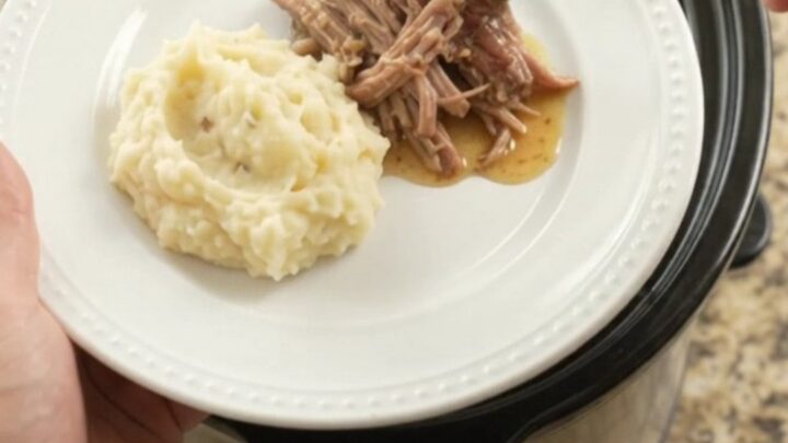 Shredded pork sirloin roast in a slow cooker with pepperoncini and buttery jus
