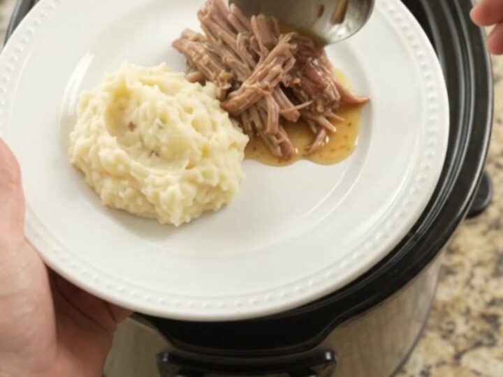 Shredded pork sirloin roast in a slow cooker with pepperoncini and buttery jus