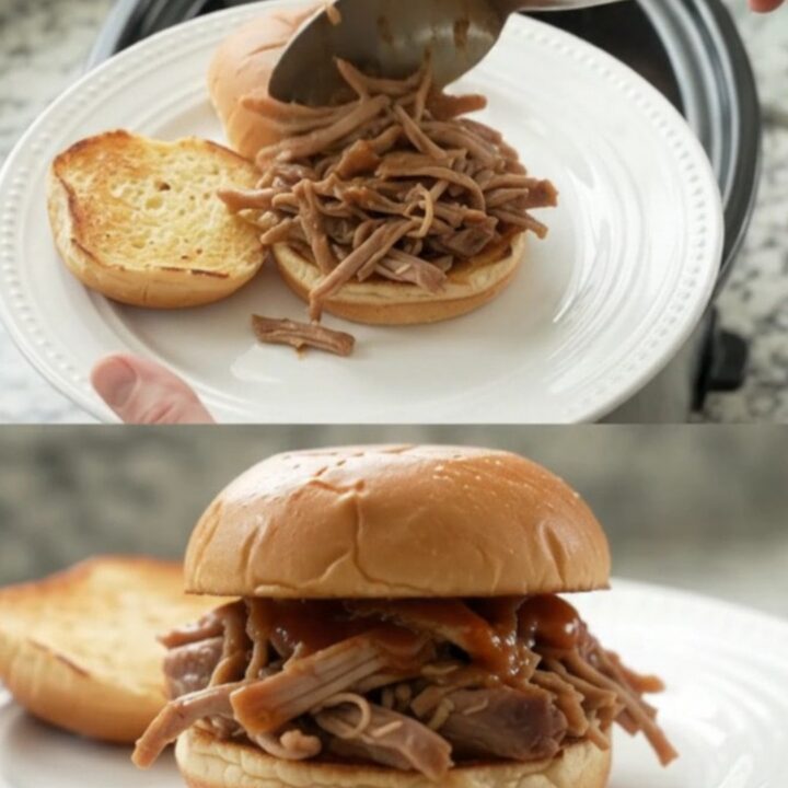 Shredded pork sirloin roast in a glossy brown gravy with whole pepperoncini, in a black slow cooker insert.