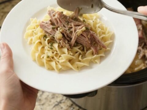 Shredded pork sirloin roast with mushrooms in a slow cooker, coated in garlic butter gravy