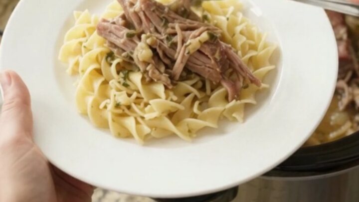 Shredded pork sirloin roast with mushrooms in a slow cooker, coated in garlic butter gravy