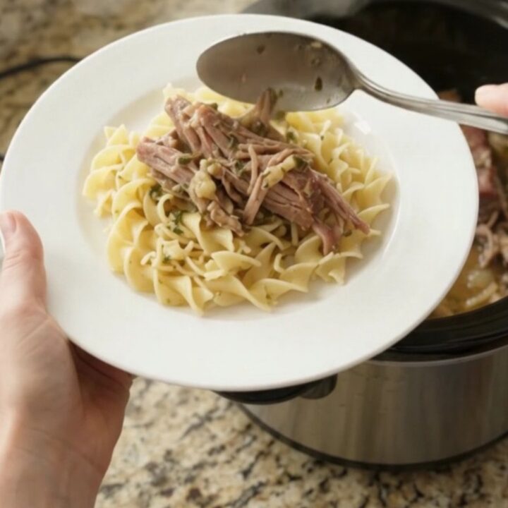 Shredded pork sirloin roast with mushrooms in a slow cooker, coated in garlic butter gravy