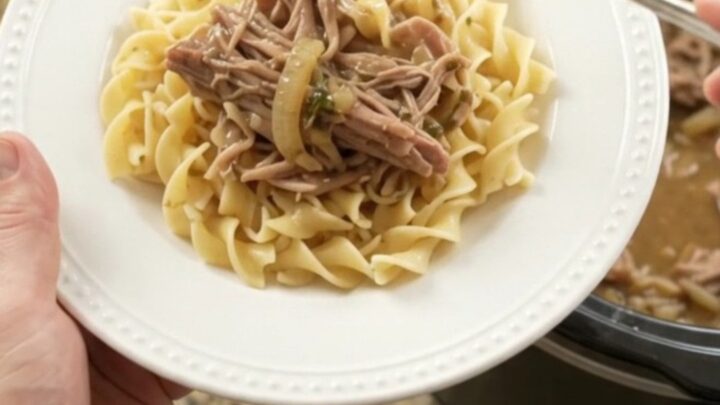 Shredded pork sirloin roast with caramelized onions and garlic butter gravy in a slow cooker
