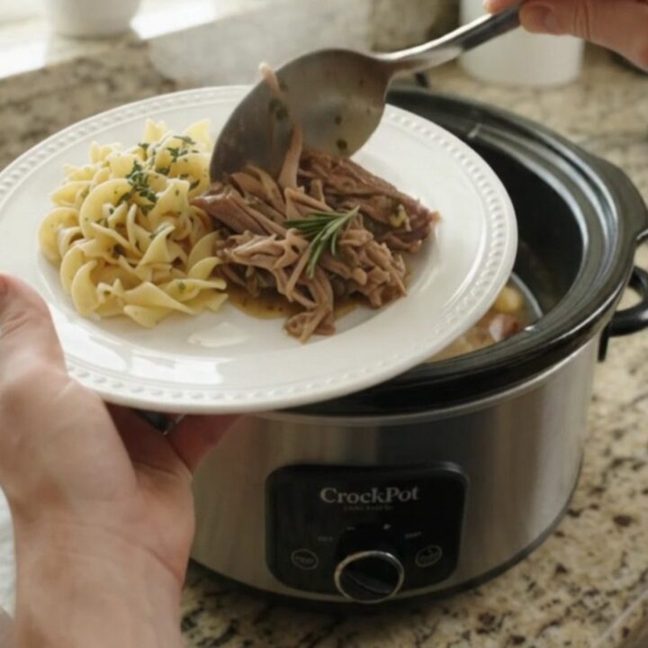 Shredded pork sirloin roast in a slow cooker with garlic and herbs, bathed in butter gravy