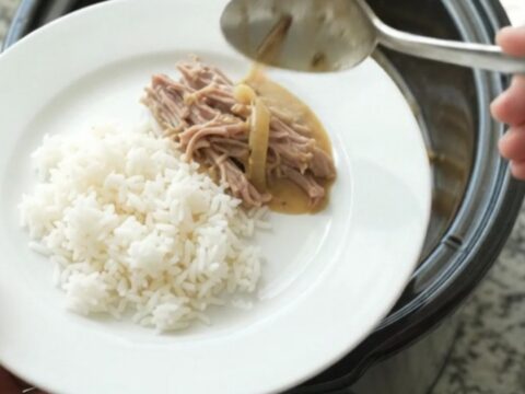 Shredded pork sirloin in a creamy Dijon onion gravy in a black slow cooker