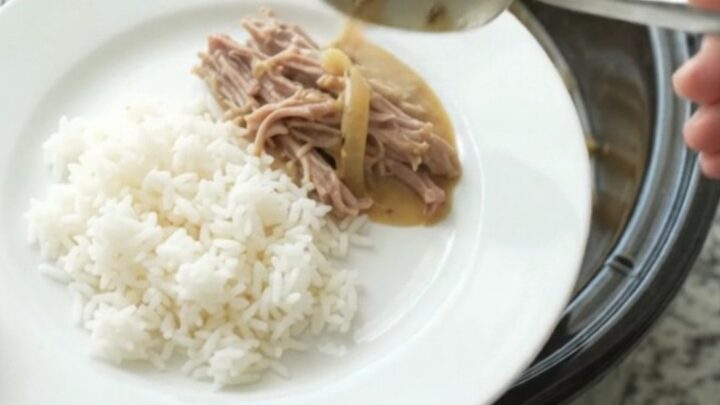Shredded pork sirloin in a creamy Dijon onion gravy in a black slow cooker