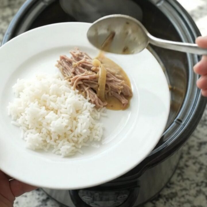 Shredded pork sirloin in a creamy Dijon onion gravy in a black slow cooker