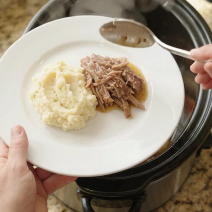Shredded pork sirloin roast with shallots and carrots in a slow cooker, topped with butter