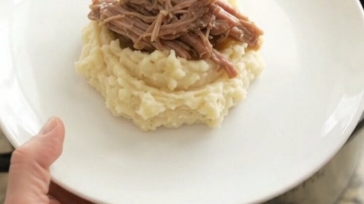 Shredded pork sirloin roast in a slow cooker with garlic and herbs