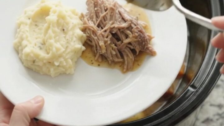 Slow cooker pork sirloin roast with butter and vegetables in a black crockpot.