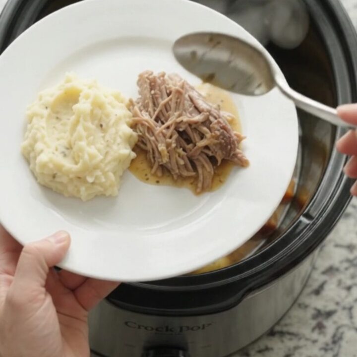 Slow cooker pork sirloin roast with butter and vegetables in a black crockpot.