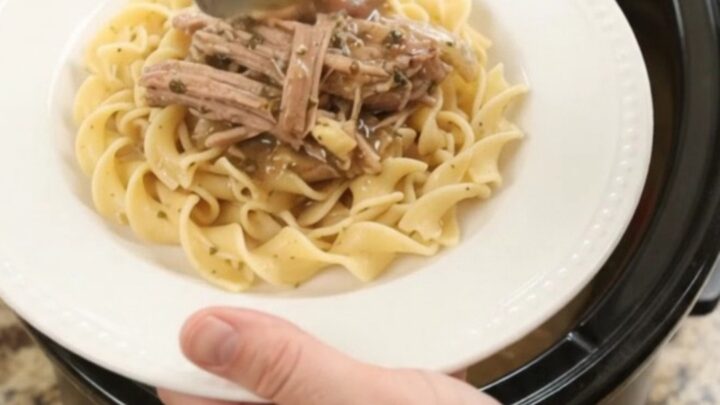 Shredded pork sirloin with peppers and onions in a slow cooker, topped with garlic-herb butter gravy.