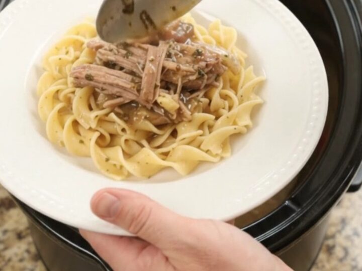 Shredded pork sirloin with peppers and onions in a slow cooker, topped with garlic-herb butter gravy.