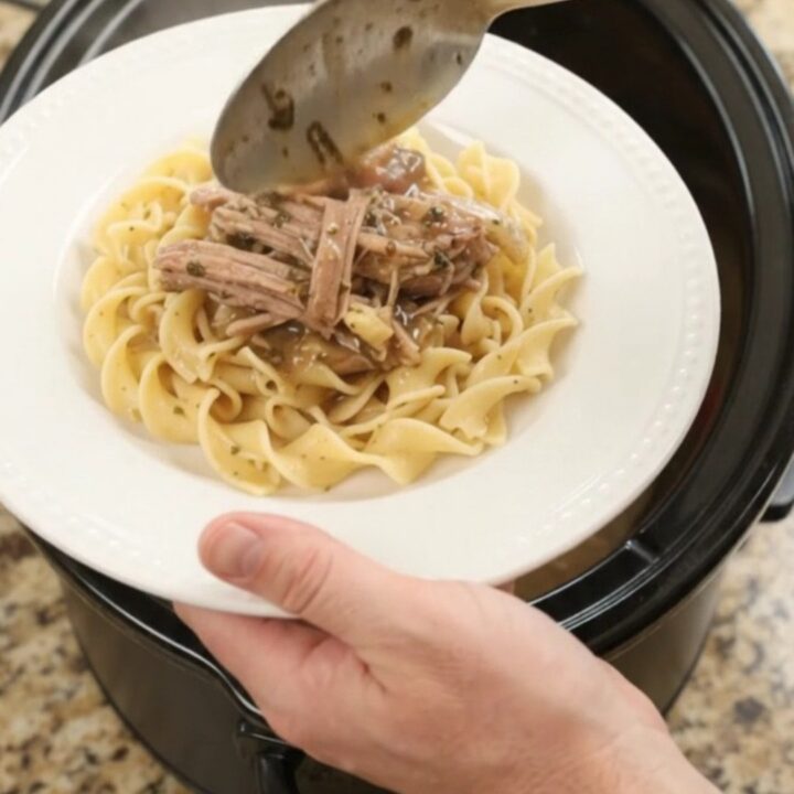 Shredded pork sirloin with peppers and onions in a slow cooker, topped with garlic-herb butter gravy.