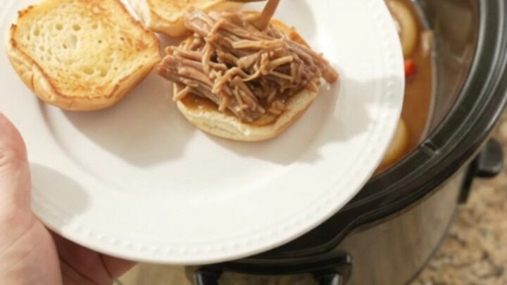Shredded pork sirloin with sweet peppers and gravy in a slow cooker, garnished with fresh parsley.