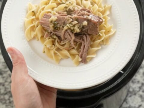 Shredded slow-cooker pork sirloin roast with portobello mushrooms and garlic-herb butter gravy in a black crockpot