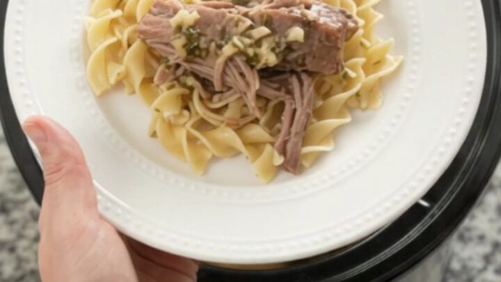 Shredded slow-cooker pork sirloin roast with portobello mushrooms and garlic-herb butter gravy in a black crockpot