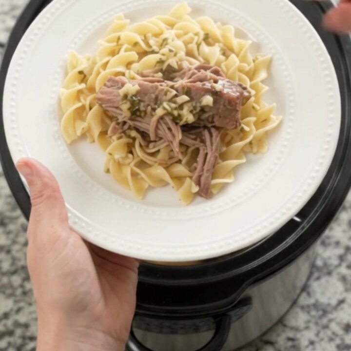 Shredded slow-cooker pork sirloin roast with portobello mushrooms and garlic-herb butter gravy in a black crockpot