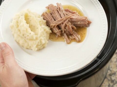 Shredded pork sirloin roast with peppers and onions in a slow cooker, golden butter sauce