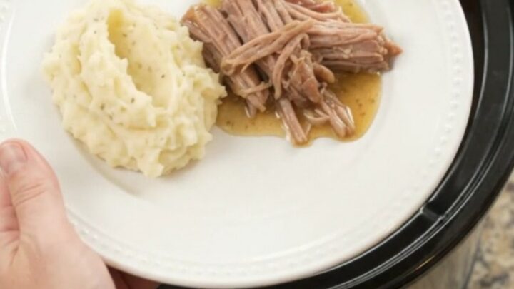 Shredded pork sirloin roast with peppers and onions in a slow cooker, golden butter sauce