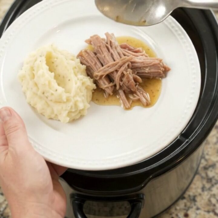 Shredded pork sirloin roast with peppers and onions in a slow cooker, golden butter sauce