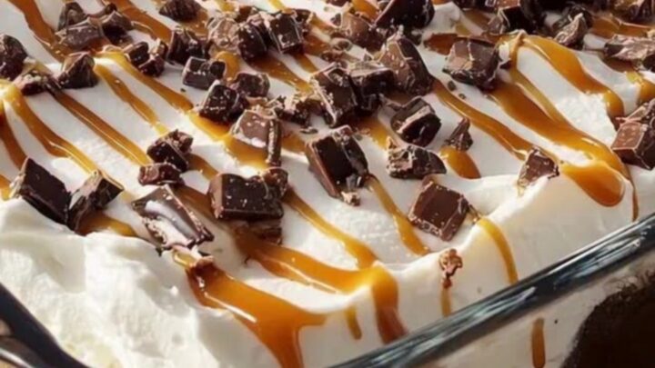 A glass casserole dish filled with Better Than Sex Cake showing distinct layers of chocolate, caramel, and cream.