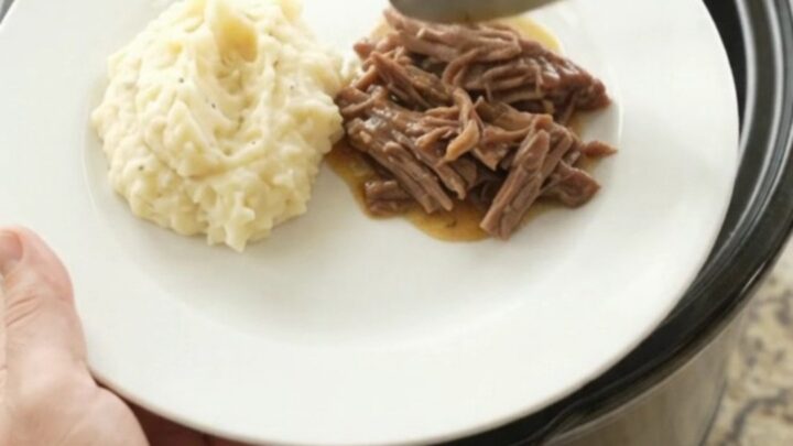 Fork-tender pepperoncini ranch butter pot roast in a slow cooker, with golden sauce and whole peppers.