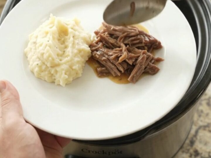 Fork-tender pepperoncini ranch butter pot roast in a slow cooker, with golden sauce and whole peppers.