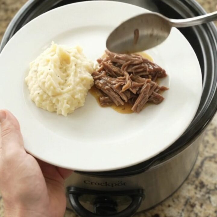 Fork-tender pepperoncini ranch butter pot roast in a slow cooker, with golden sauce and whole peppers.