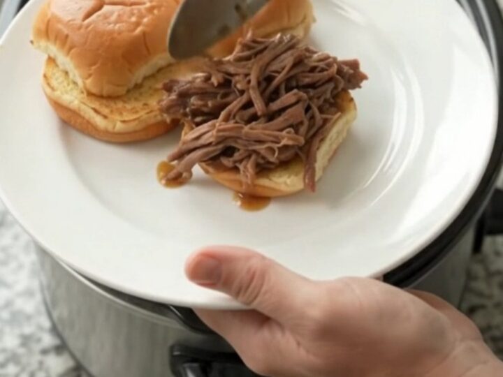 Pepperoncini ranch pot roast in a slow cooker, shredded beef in glossy gravy with whole pepperoncini peppers