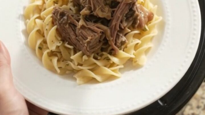 Slow-cooker beef roast with mushrooms and garlic butter gravy in a black ceramic crockpot