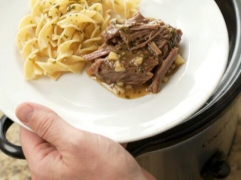 Fork-tender beef roast in a slow cooker with rich gravy and melted butter