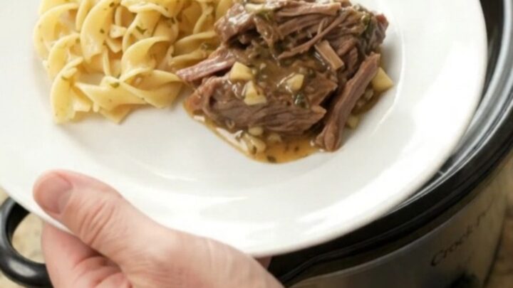 Fork-tender beef roast in a slow cooker with rich gravy and melted butter