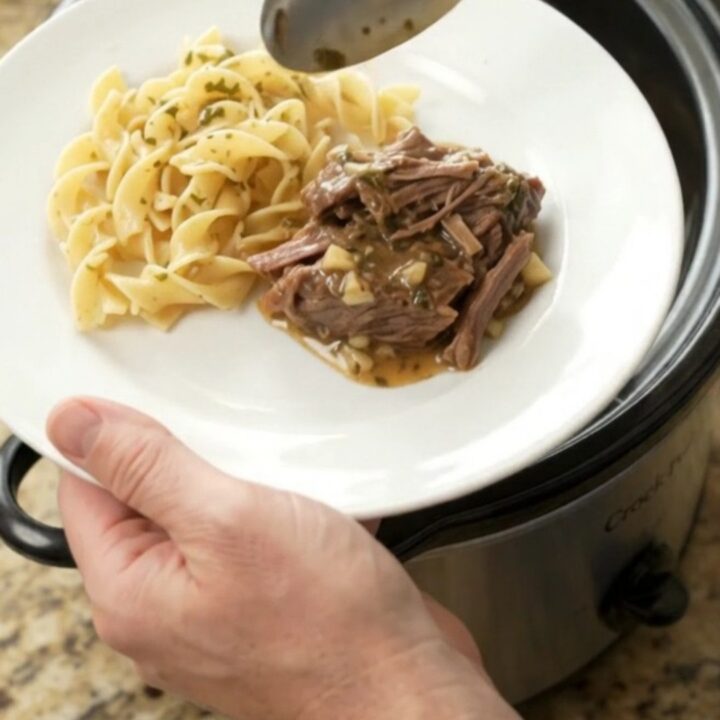 Fork-tender beef roast in a slow cooker with rich gravy and melted butter