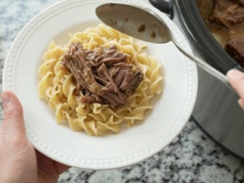 Slow-cooker bottom round roast with pearl onions and gravy in a black crockpot