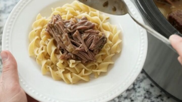 Slow-cooker bottom round roast with pearl onions and gravy in a black crockpot