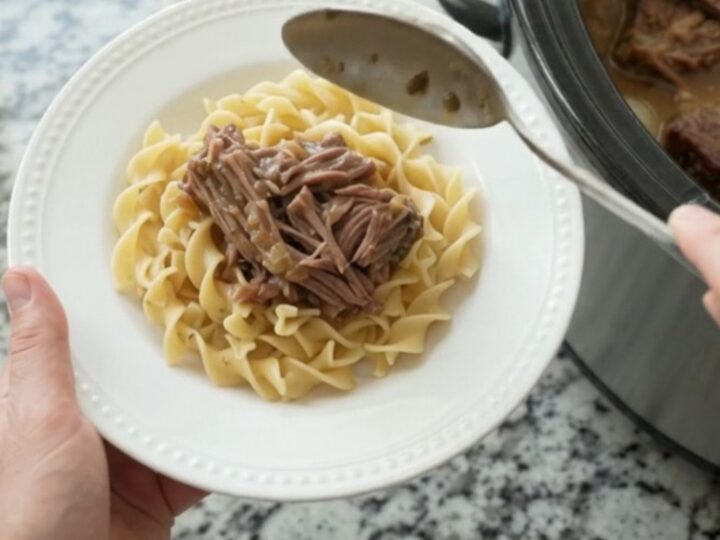 Slow-cooker bottom round roast with pearl onions and gravy in a black crockpot