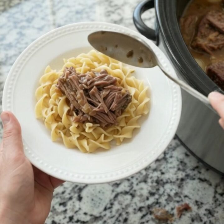 Slow-cooker bottom round roast with pearl onions and gravy in a black crockpot