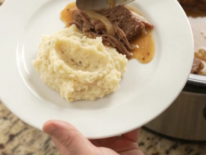 A fork-tender beef roast with caramelized onions and butter sauce in a slow cooker
