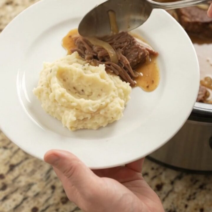 A fork-tender beef roast with caramelized onions and butter sauce in a slow cooker
