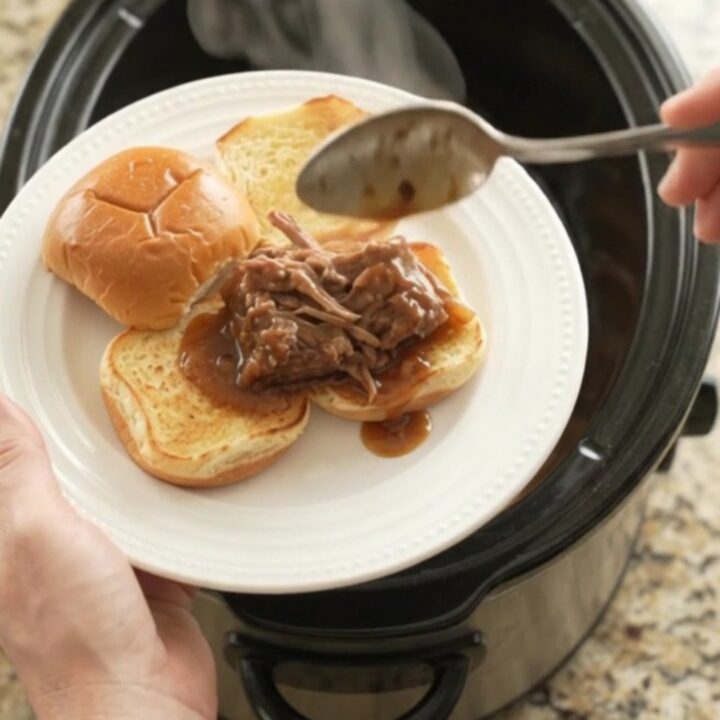 Shredded beef and onions in a dark gravy in a slow cooker