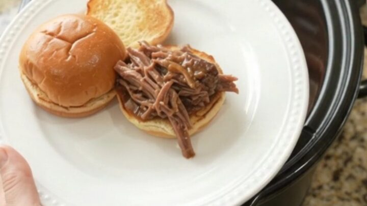 Shredded beef roast with carrots and shallots in rich gravy in a slow cooker