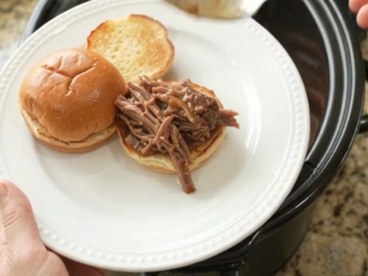 Shredded beef roast with carrots and shallots in rich gravy in a slow cooker