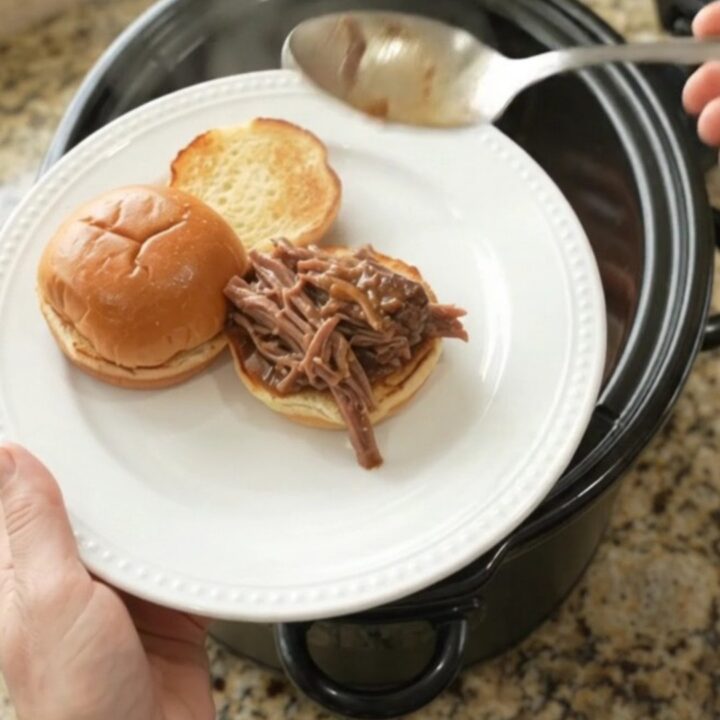 Shredded beef roast with carrots and shallots in rich gravy in a slow cooker