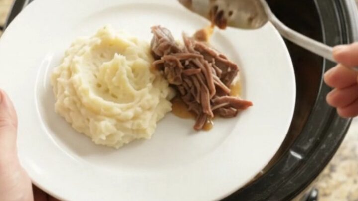 Fork-tender beef roast with shallots and carrots in a slow cooker, glistening with butter sauce.